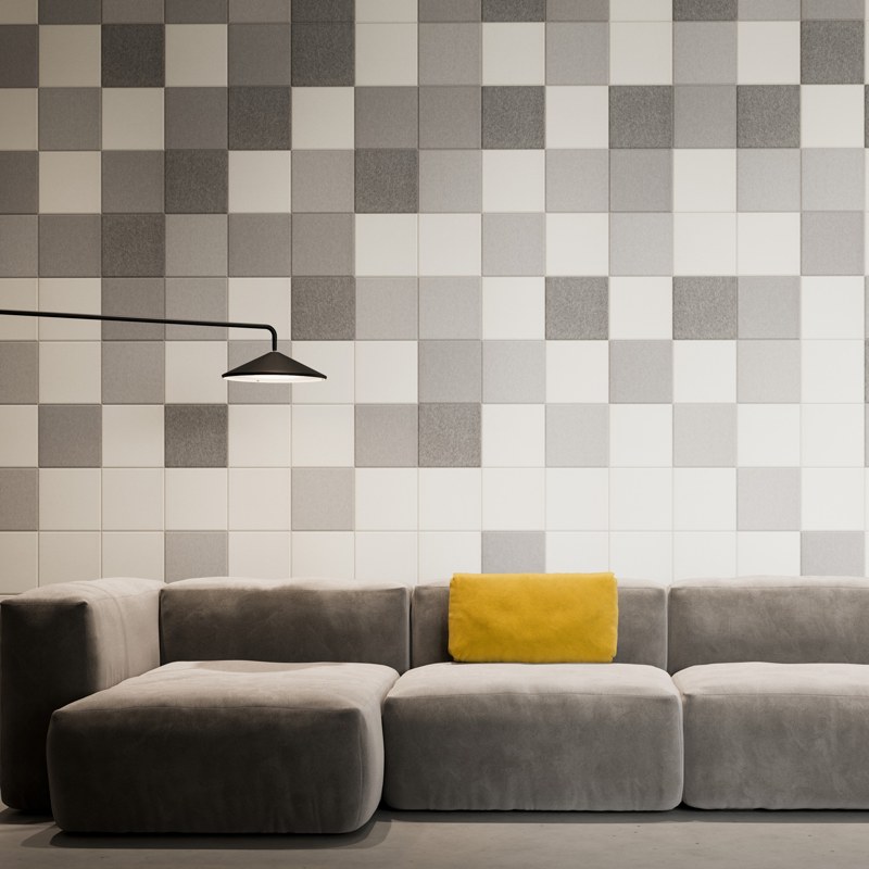 Square acoustic wall tiles in mixed greys behind a sofa